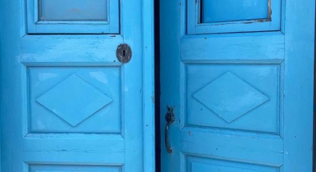 Bright blue wooden doors with one door slightly ajar